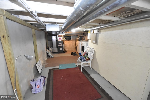 unfinished basement featuring heating unit and washer / dryer