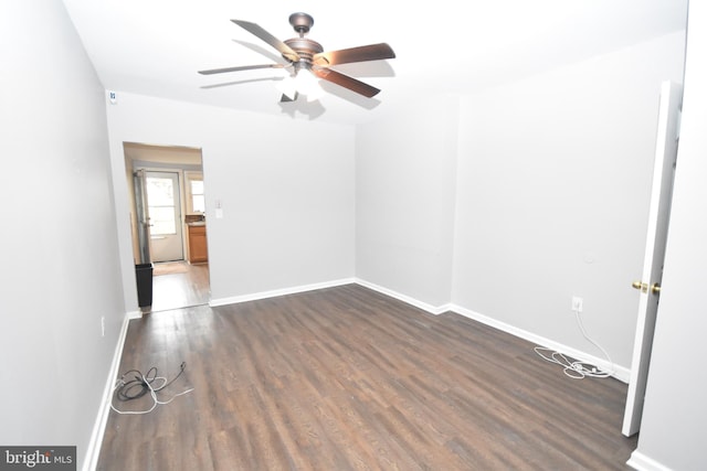 spare room with wood finished floors, a ceiling fan, and baseboards