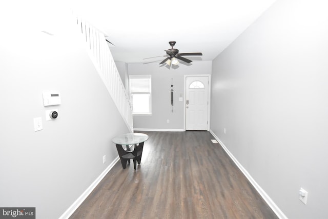 foyer entrance with stairway, baseboards, dark wood finished floors, and a ceiling fan