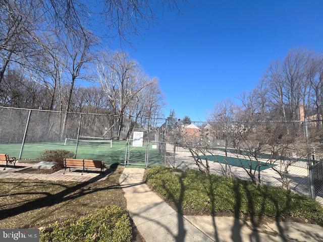 exterior space with a tennis court and fence