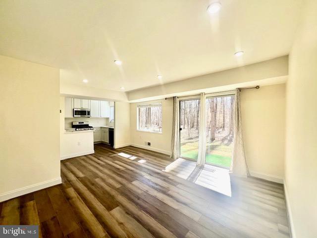 unfurnished living room featuring dark wood-style floors, recessed lighting, and baseboards