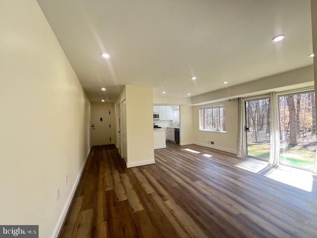 unfurnished living room featuring recessed lighting, dark wood finished floors, and baseboards