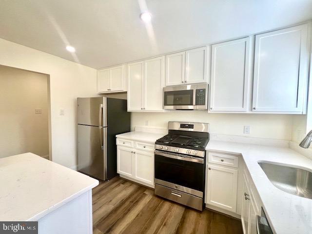 kitchen with appliances with stainless steel finishes, white cabinetry, and a sink