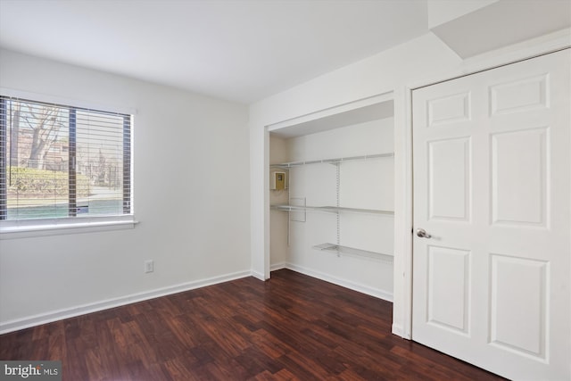 unfurnished bedroom with a closet, dark wood finished floors, and baseboards