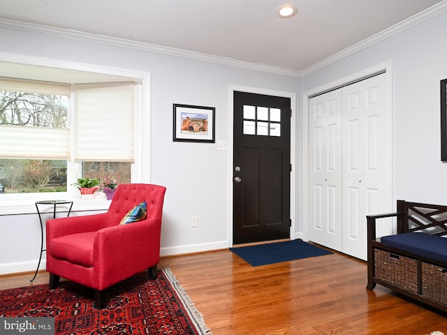 foyer featuring baseboards, crown molding, and wood finished floors