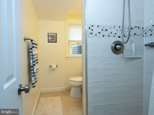 bathroom featuring tile patterned flooring, baseboards, a tile shower, and toilet