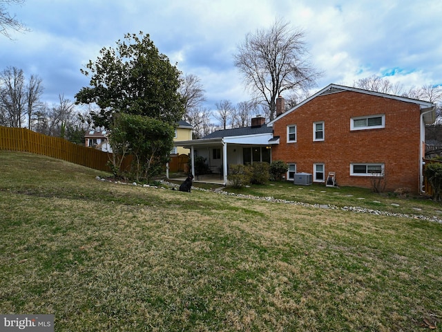 rear view of house with a chimney, fence, a yard, a patio area, and brick siding