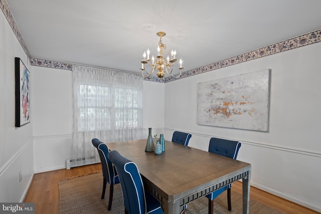 dining space with a baseboard heating unit, a chandelier, baseboards, and wood finished floors