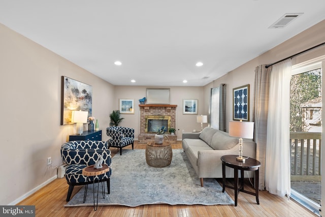 living area with baseboards, a fireplace, visible vents, and hardwood / wood-style floors