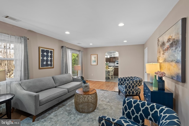 living area featuring arched walkways, recessed lighting, visible vents, wood finished floors, and baseboards