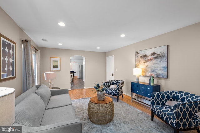 living area with arched walkways, visible vents, recessed lighting, and wood finished floors