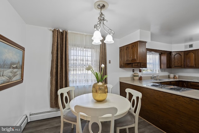 dining room with a baseboard heating unit, visible vents, a chandelier, and dark wood finished floors