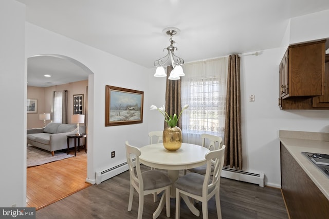 dining room featuring baseboards, arched walkways, baseboard heating, and dark wood finished floors