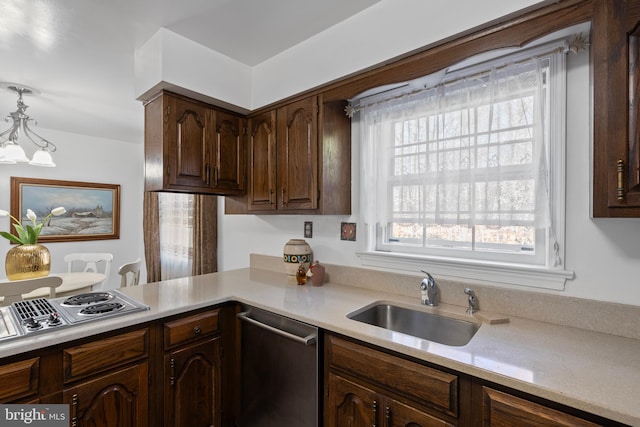 kitchen featuring decorative light fixtures, light countertops, appliances with stainless steel finishes, a sink, and dark brown cabinetry