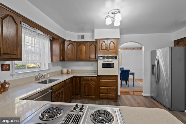 kitchen with arched walkways, a sink, visible vents, light countertops, and appliances with stainless steel finishes