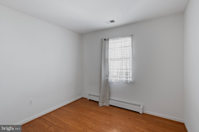 spare room featuring visible vents, baseboards, baseboard heating, and wood finished floors