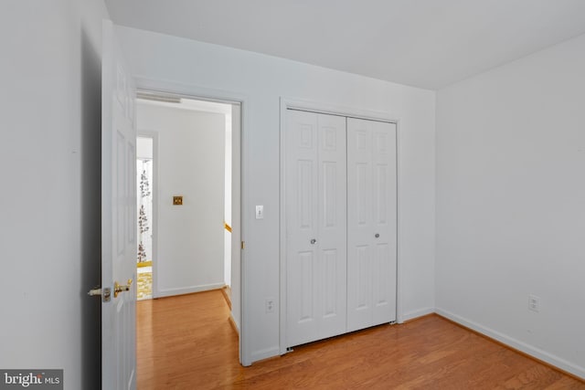 unfurnished bedroom with a closet, wood finished floors, and baseboards