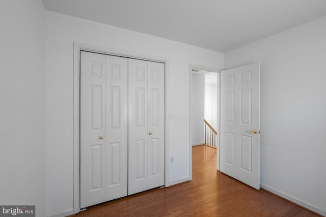 unfurnished bedroom with a closet, baseboards, and wood finished floors