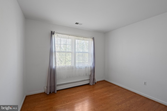 unfurnished room with visible vents, a baseboard radiator, light wood-style flooring, and baseboards