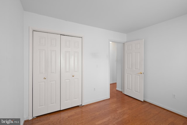 unfurnished bedroom featuring a closet, wood finished floors, and baseboards