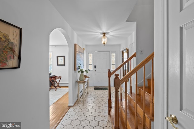 foyer with arched walkways, stairway, and plenty of natural light