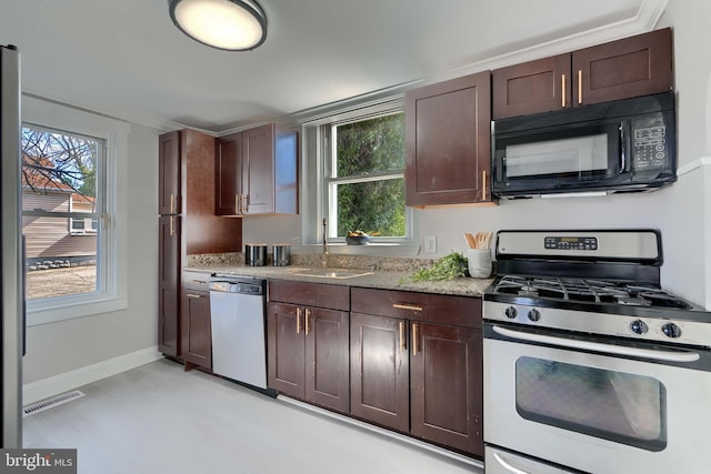 kitchen featuring dark brown cabinetry, light stone countertops, baseboards, and stainless steel appliances