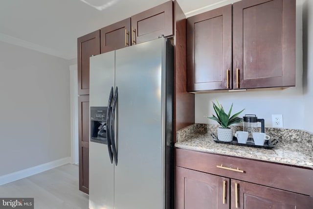 kitchen with baseboards, stainless steel fridge, crown molding, and light stone countertops