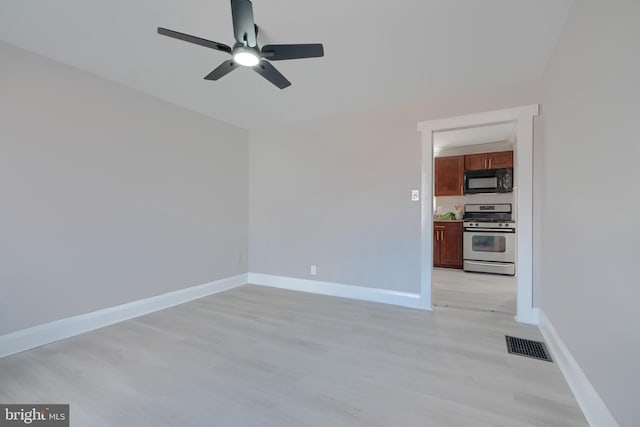 spare room featuring visible vents, light wood-style flooring, a ceiling fan, and baseboards