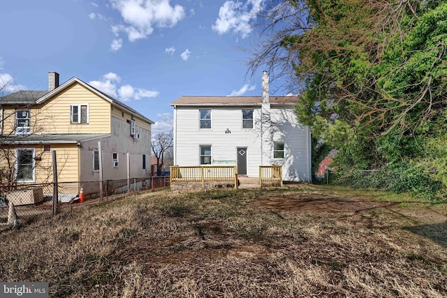 back of property with fence, a chimney, and a wooden deck