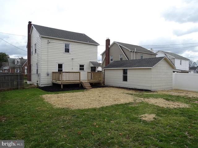 rear view of property featuring a deck, a yard, an outdoor structure, and a fenced backyard