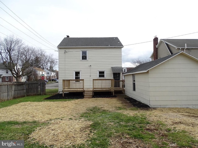 back of house featuring fence, a deck, and a lawn