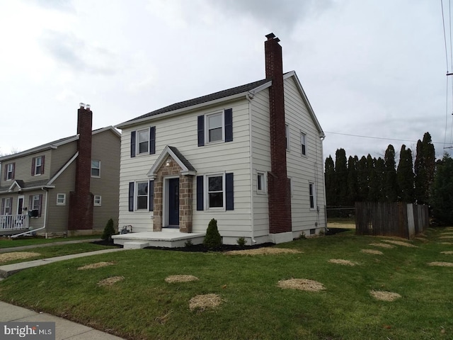 view of front facade featuring a chimney, fence, and a front lawn