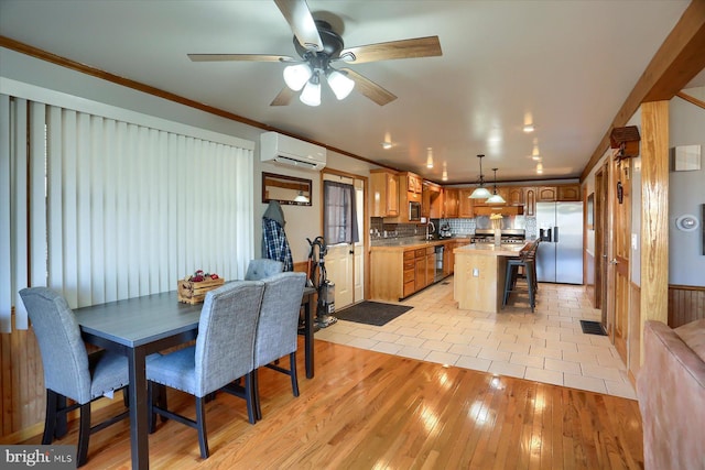 kitchen featuring a center island, an AC wall unit, ornamental molding, stainless steel refrigerator with ice dispenser, and a sink