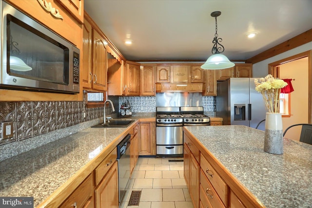 kitchen with tasteful backsplash, tile counters, appliances with stainless steel finishes, brown cabinetry, and a sink