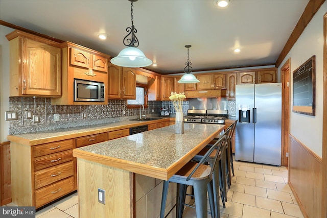 kitchen with a kitchen island, under cabinet range hood, tile countertops, stainless steel appliances, and a sink