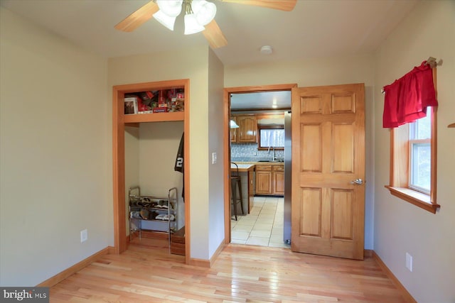 interior space with light wood finished floors, baseboards, and a sink