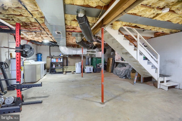 unfinished basement with visible vents, stairway, washing machine and dryer, water heater, and concrete block wall