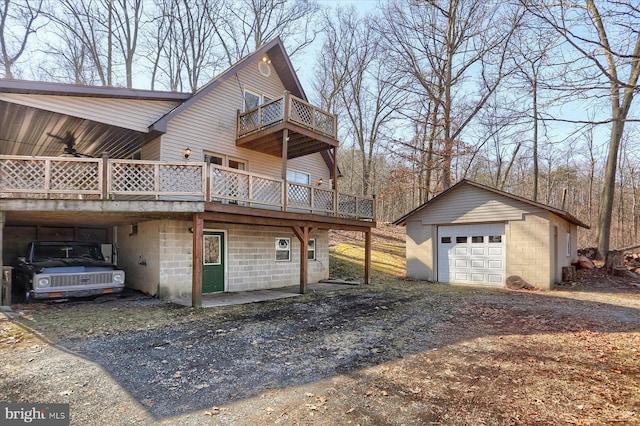 view of property exterior with an outbuilding, a ceiling fan, a garage, dirt driveway, and a deck