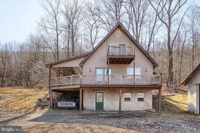 rear view of property with a carport, driveway, and a deck