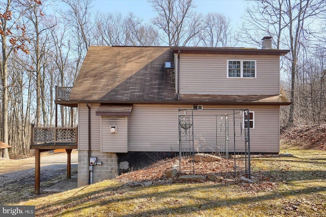 view of home's exterior with a shingled roof, a wooden deck, and a chimney