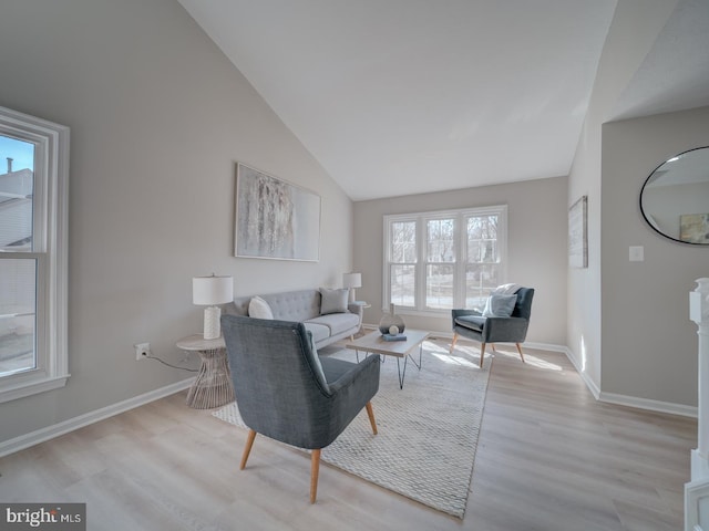 living room featuring baseboards, high vaulted ceiling, and light wood finished floors