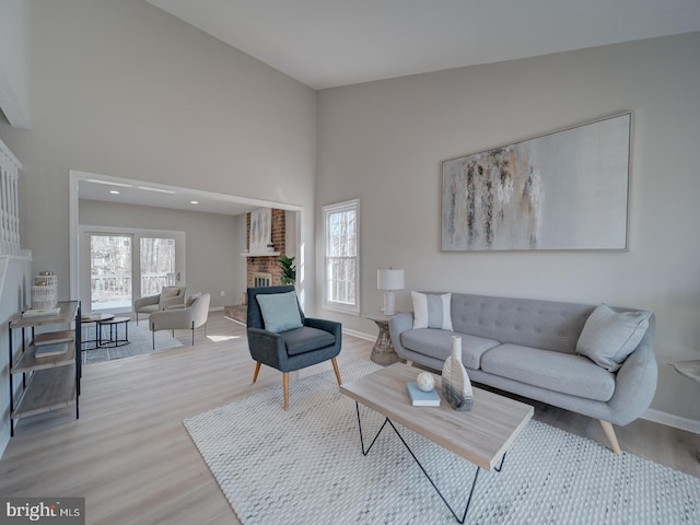 living room featuring a fireplace, light wood-style floors, and baseboards