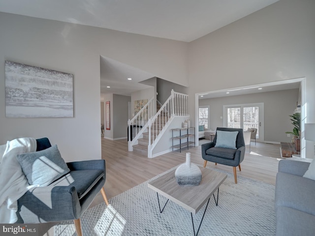 living area featuring baseboards, stairs, a high ceiling, and wood finished floors