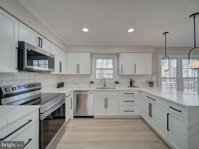 kitchen featuring a sink, stainless steel appliances, a peninsula, and white cabinets