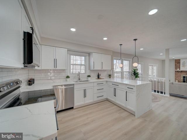 kitchen with a sink, light stone counters, stainless steel dishwasher, and a peninsula