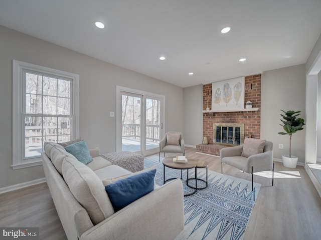 living area featuring recessed lighting, a fireplace, baseboards, and wood finished floors