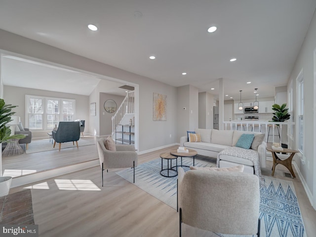 living room with light wood-type flooring, stairway, baseboards, and recessed lighting