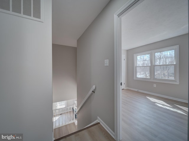 stairway featuring visible vents, baseboards, and wood finished floors