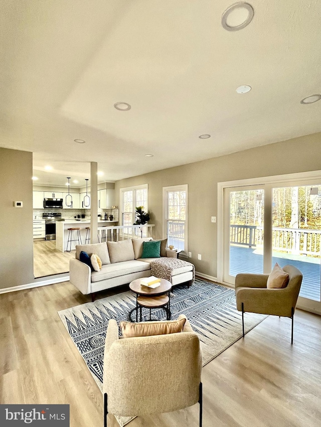 living room featuring light wood finished floors, recessed lighting, and baseboards