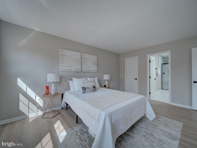 bedroom featuring light wood-style floors, baseboards, and connected bathroom